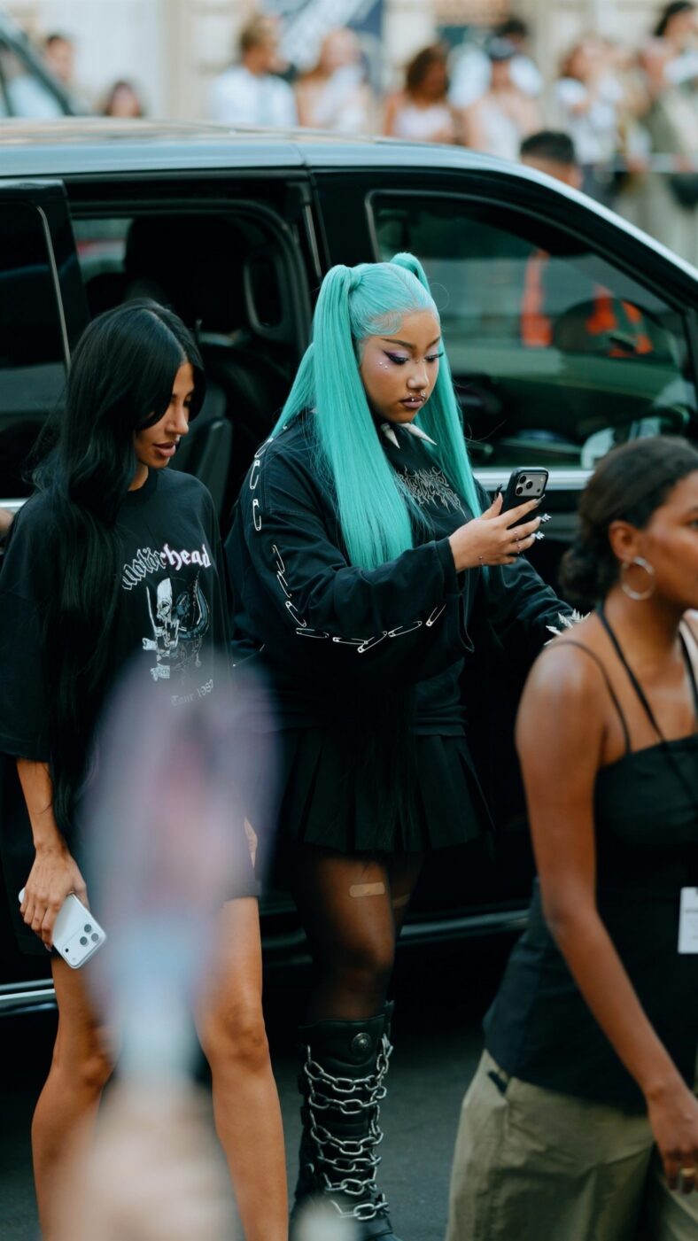 North West usa roupa grunge preta com longos cabelos azuis presos em tranças altas.