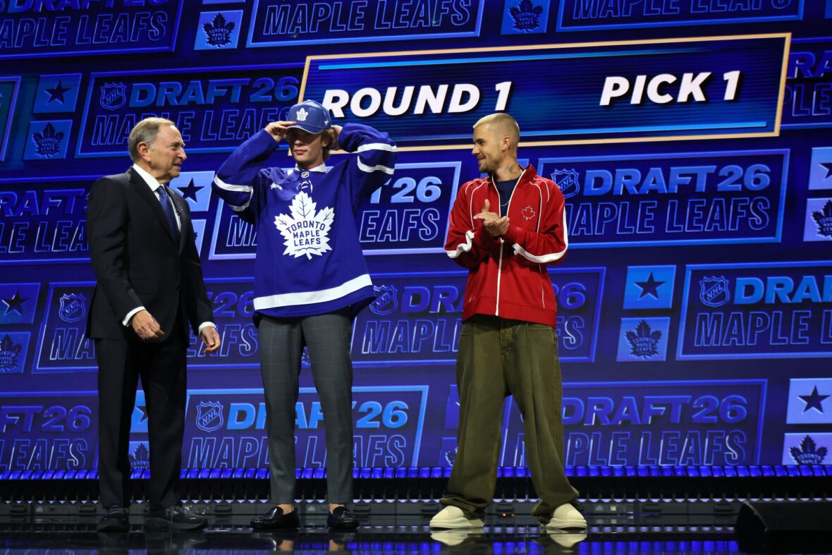 O comissário da NHL, Gary Bettman, entrega o chapéu a Gavin McKenna, do Canadá, enquanto o cantor Justin Bieber observa McKenna