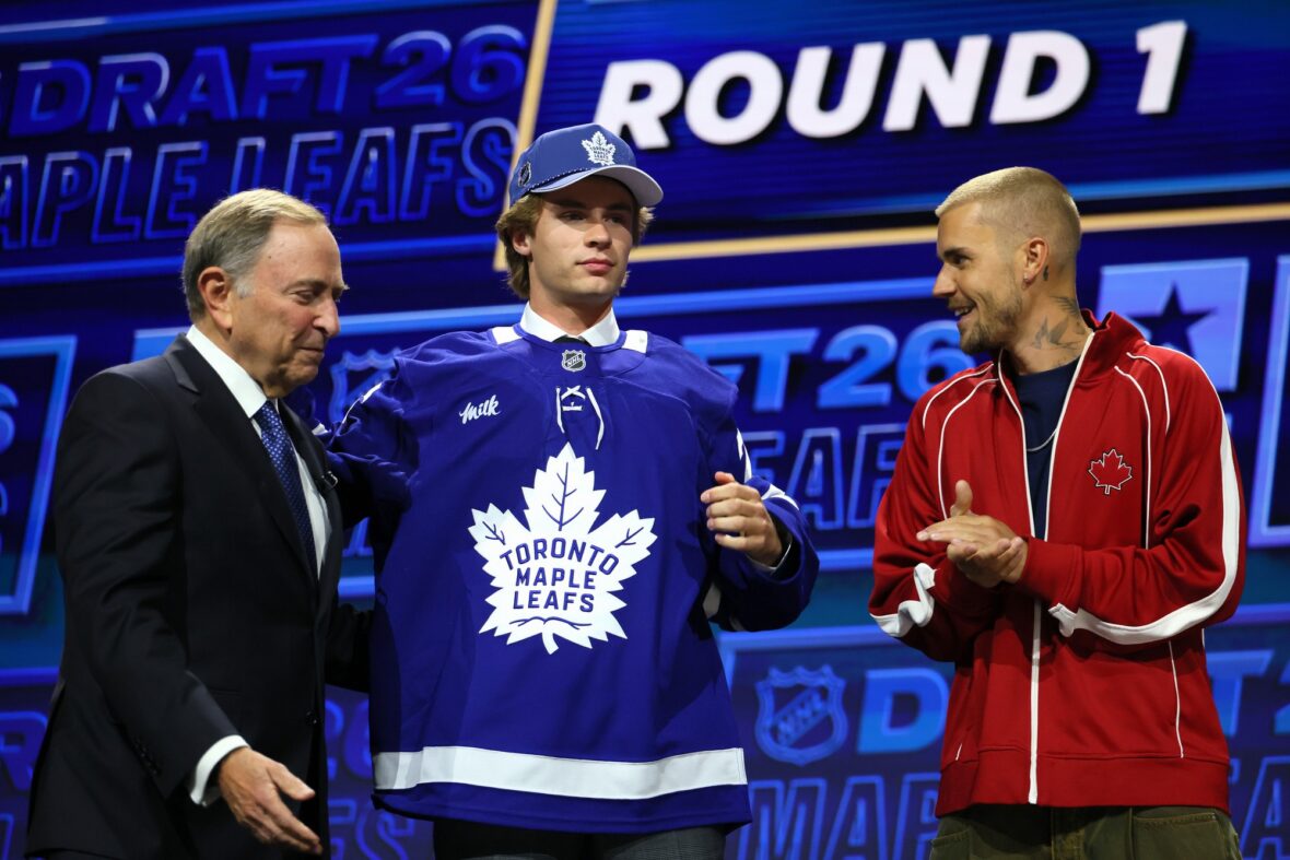 O comissário da NHL, Gary Bettman, entrega o chapéu a Gavin McKenna, do Canadá, enquanto o cantor Justin Bieber observa McKenna