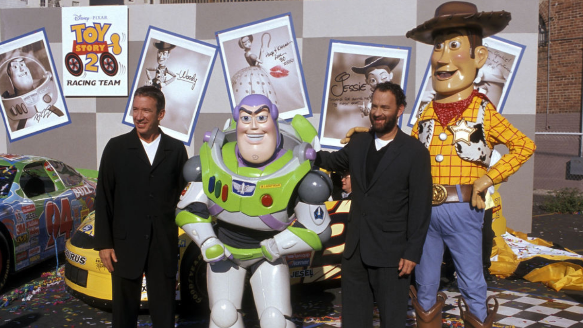 Actor Tim Allen and actor Tom Hanks standing with Buzz Lightyear and Woody figures at an event.