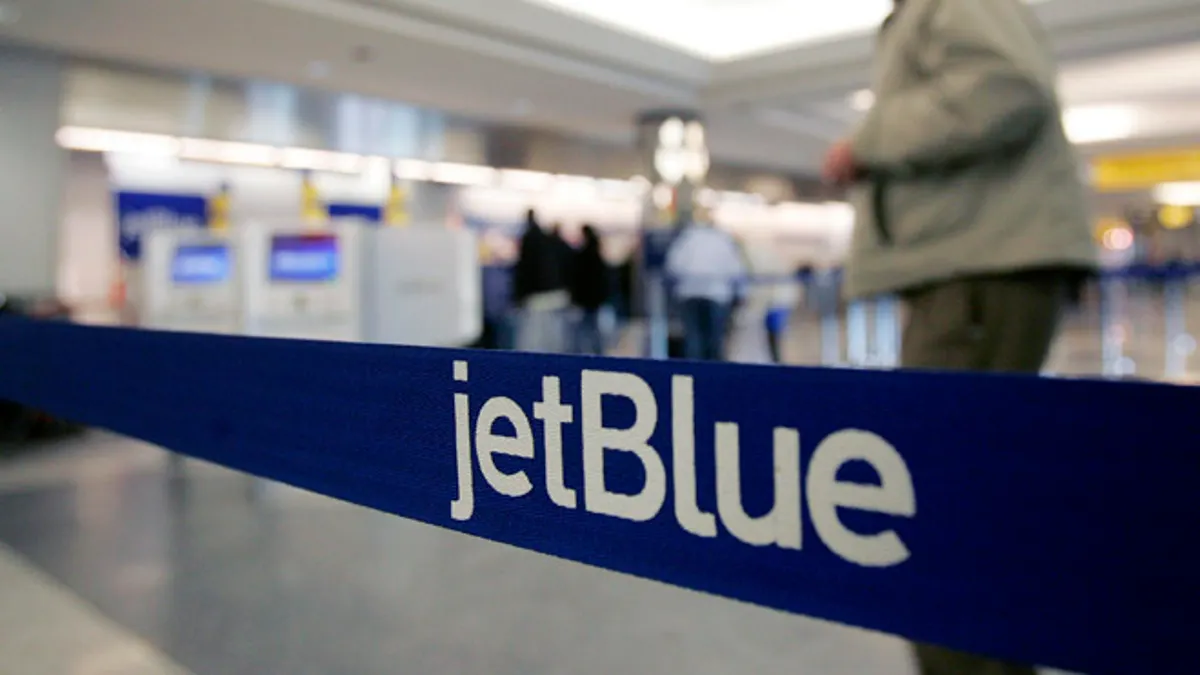 FILE - In this Wednesday Feb. 1, 2006, file photo, a pedestrian makes his way to the e-ticket counter of JetBlue at New York's LaGuardia Airport. Starting in 2014, JetBlue, the all-coach airline, plans to offer 16 lie-flat seats on flights between New York and Los Angeles and San Francisco. Itâs the first time the egalitarian carrier will have a second class of service. (AP Photo/Frank Franklin II, File)