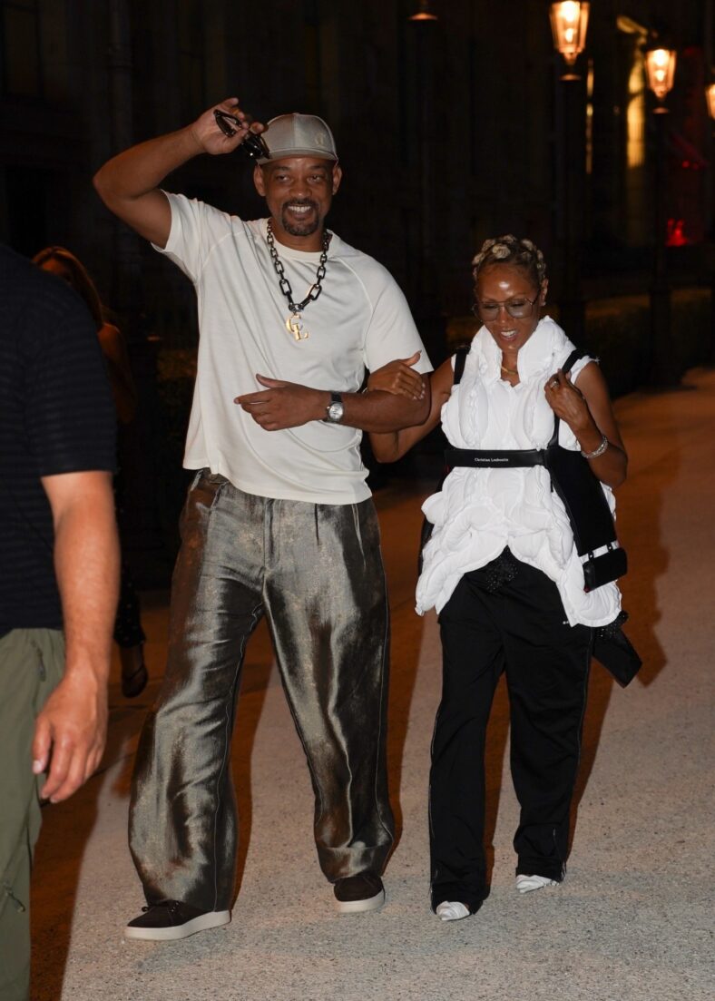 Will Smith sorri enquanto caminha de braços dados com Jada Pinkett Smith após um raro jantar em Paris.