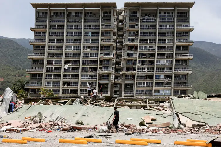 People inspect the rubble of a collapsed building after earthquakes hit the country, in La Guaira, Venezuela, June 25, 2026. REUTERS/Gaby Oraa      TPX IMAGES OF THE DAY