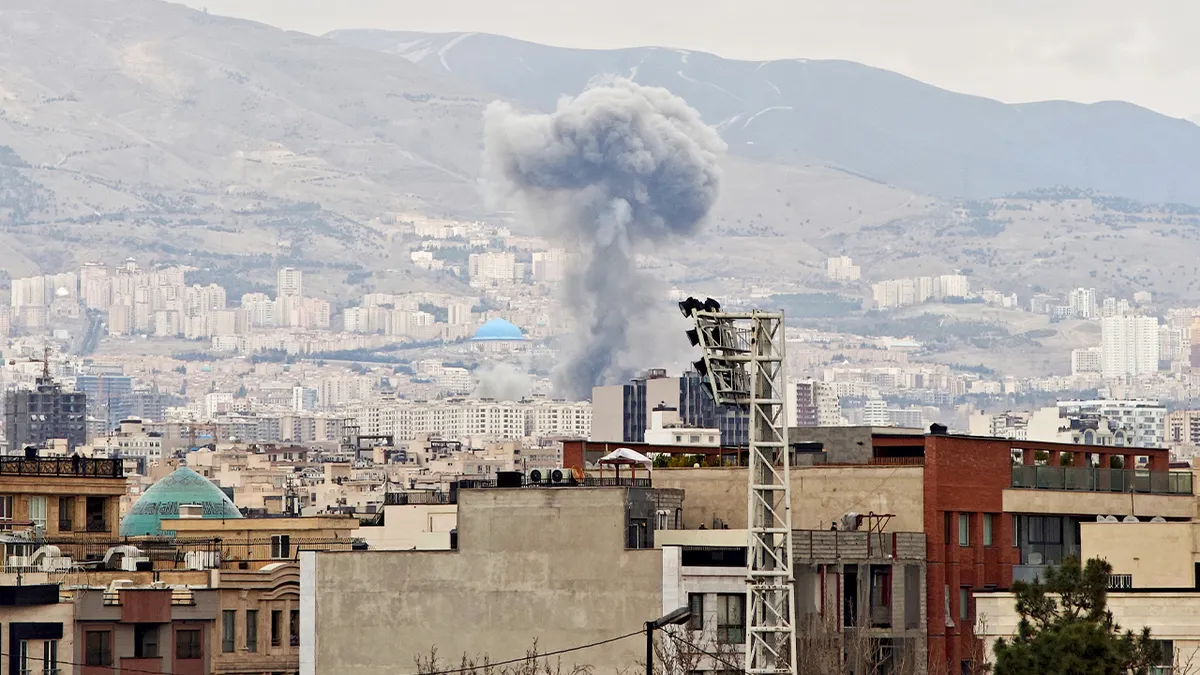 A tall column of smoke rising over Tehran after an explosion
