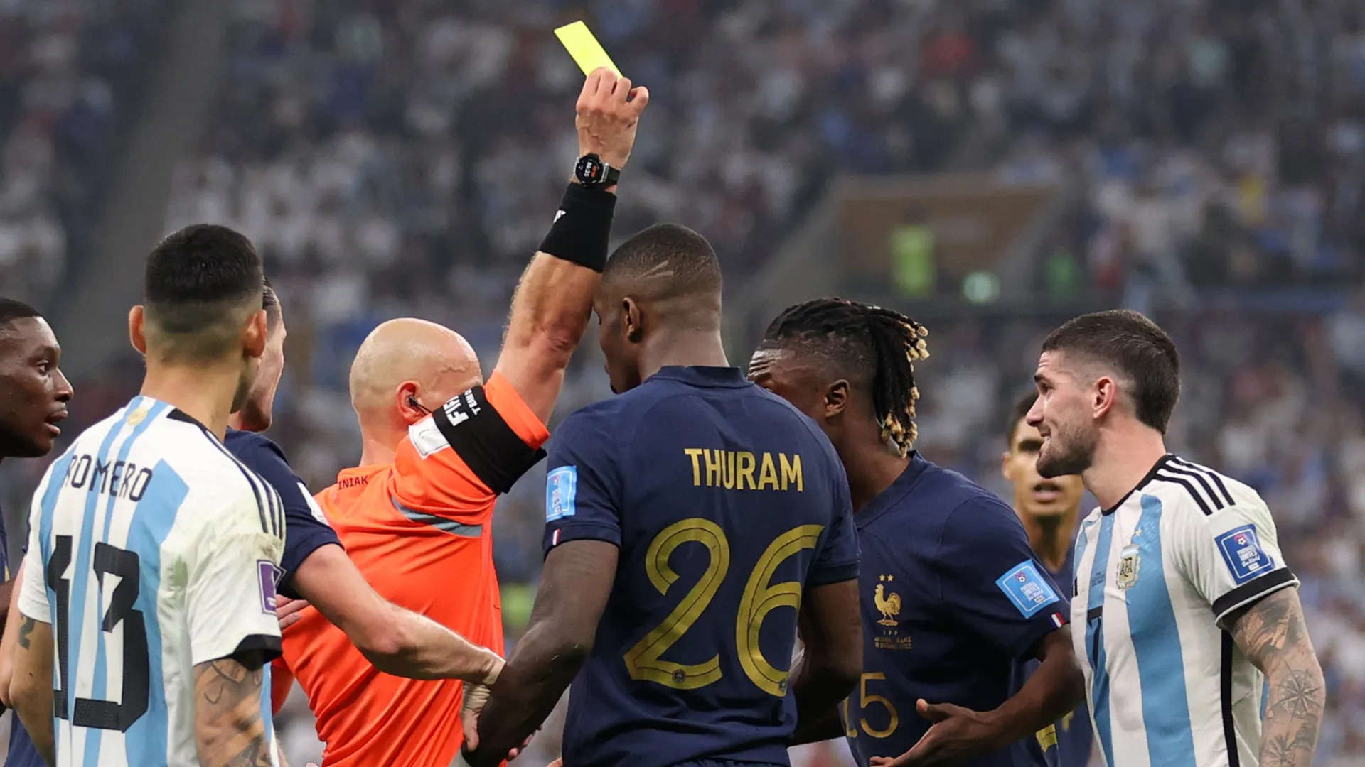 Marcus Thuram, da França, recebe cartão amarelo do árbitro Szymon Marciniak.