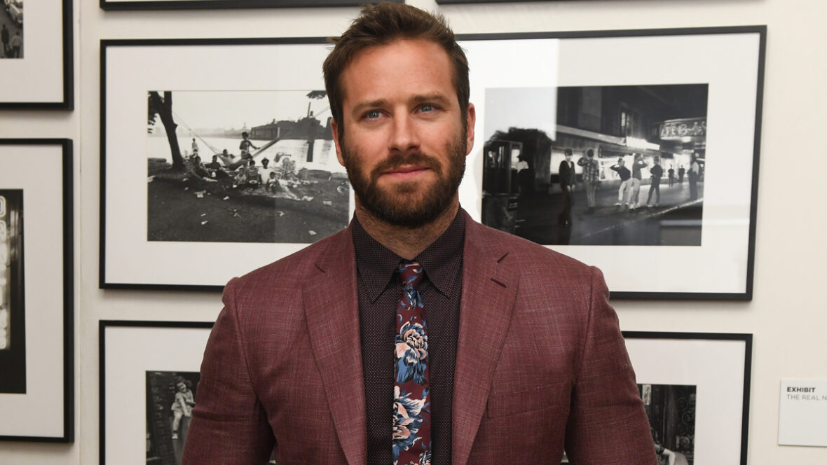 exército-martelo-cidadão-vigilante Armie Hammer posa com paletó cor de vinho e gravata floral em um evento interno.