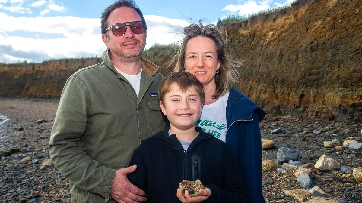 Charlie Orchard-Lisle standing with his family while holding tooth
