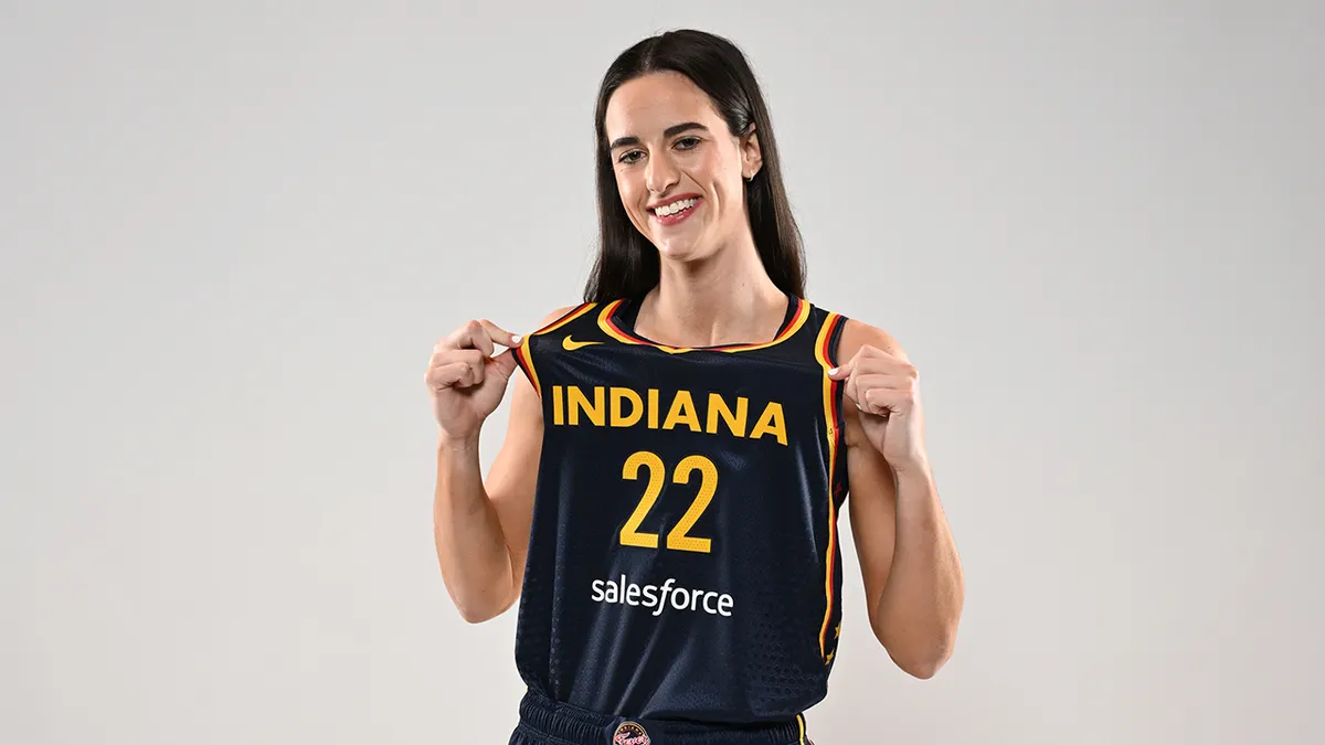 Caitlin Clark posing with Indiana Fever jersey at Gainbridge Fieldhouse