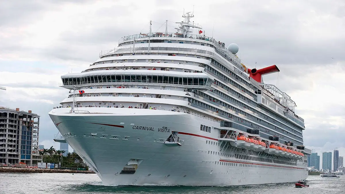 The Carnival Cruise Ship Carnival Vista sailing escorted by a coast guard vessel in Miami harbor entrance.