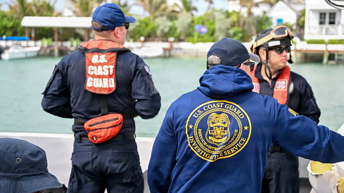 U.S. Coast Guard investigators stand on a boat.