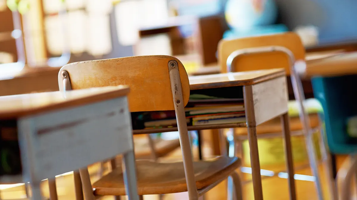 A classroom with empty wooden desks and chairs.