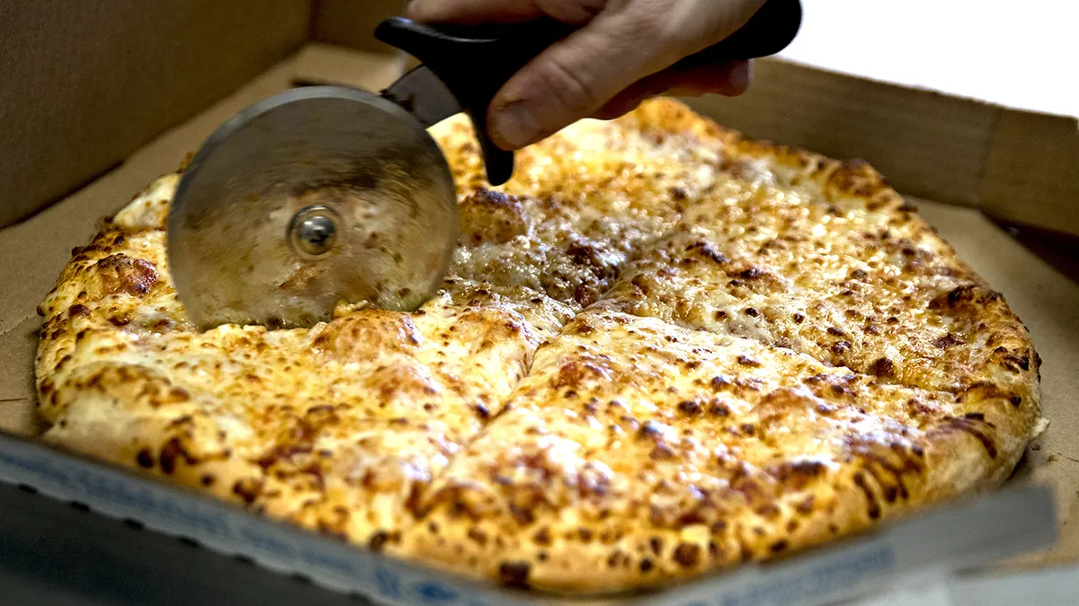 Employee slicing Domino's pizza inside a store