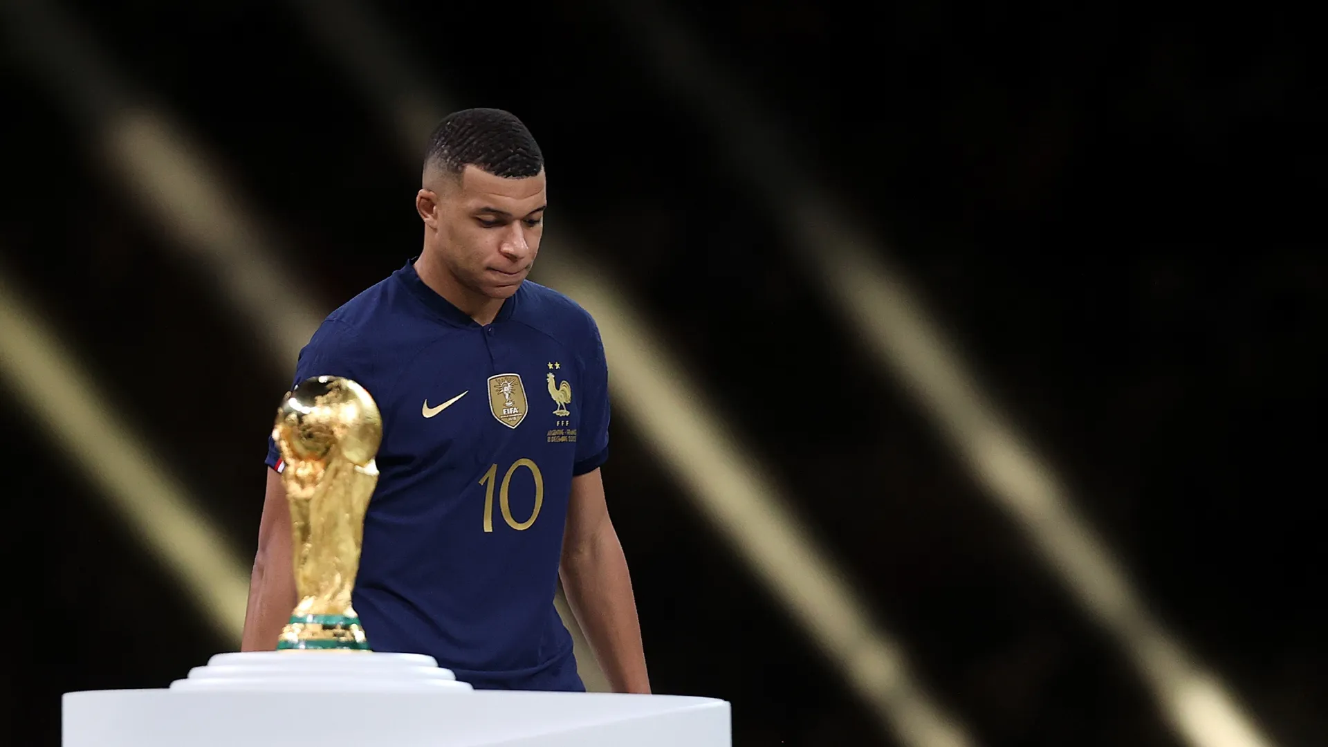 Kylian Mbappe, da França, passa pelo troféu da Copa do Mundo FIFA de 2022.