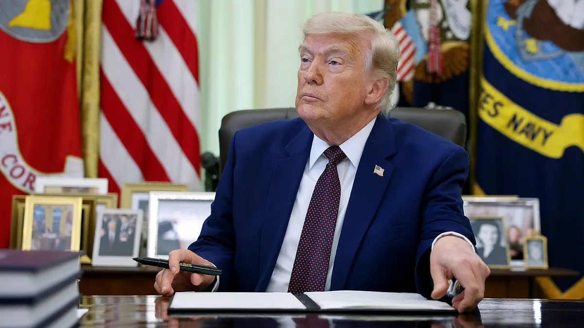 President Donald Trump signing an executive order in the Oval Office of the White House.