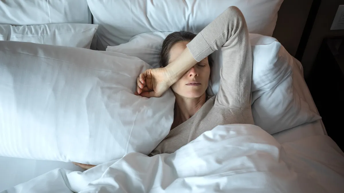 Young woman waking up in bed looking tired and suffering from insomnia