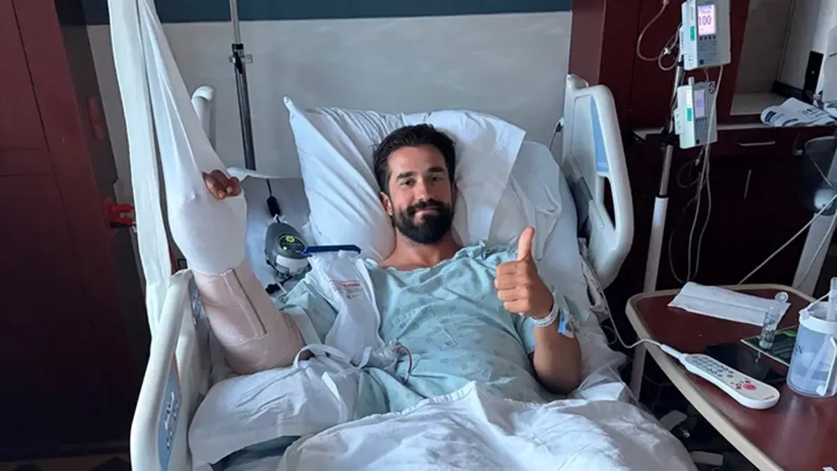 Daniel Crago laying in a hospital bed with his thumb up.
