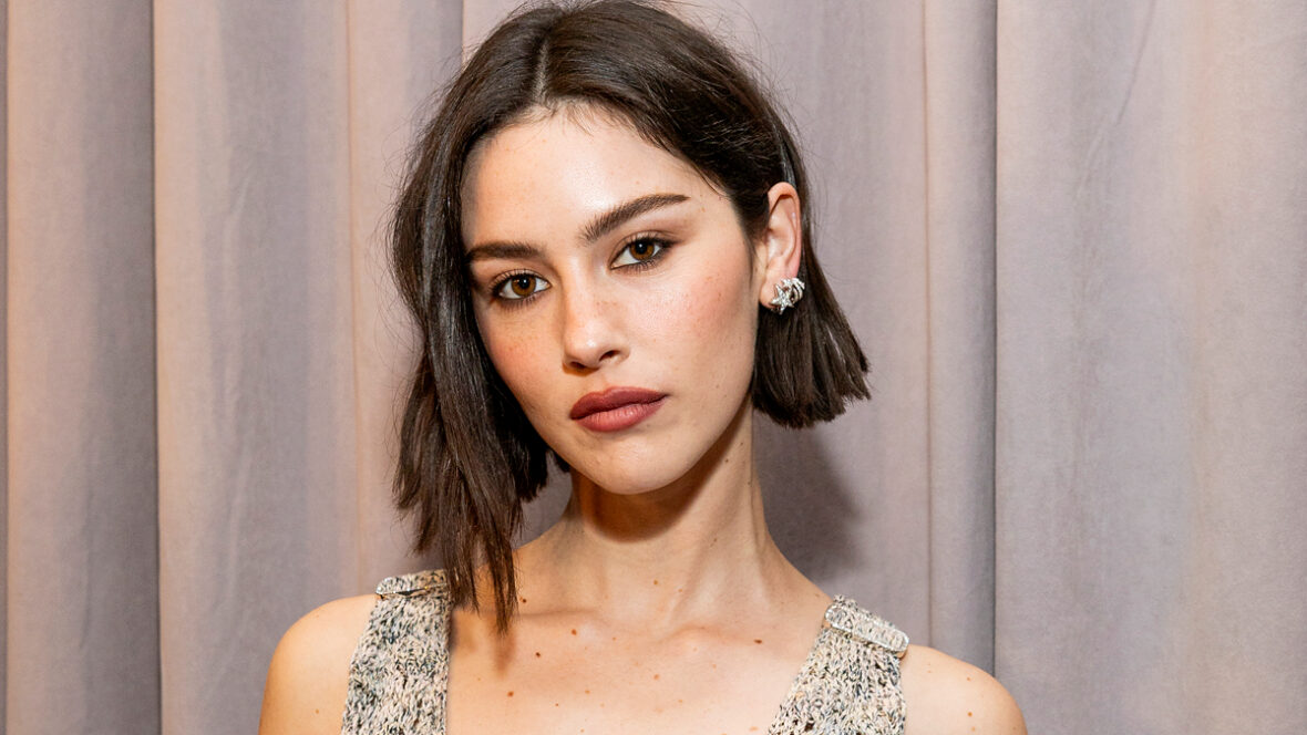 Gracie Abrams posa para um retrato em close no Grammy de 2025, usando um vestido texturizado sem mangas e seu cabelo curto e escuro penteado em bob.