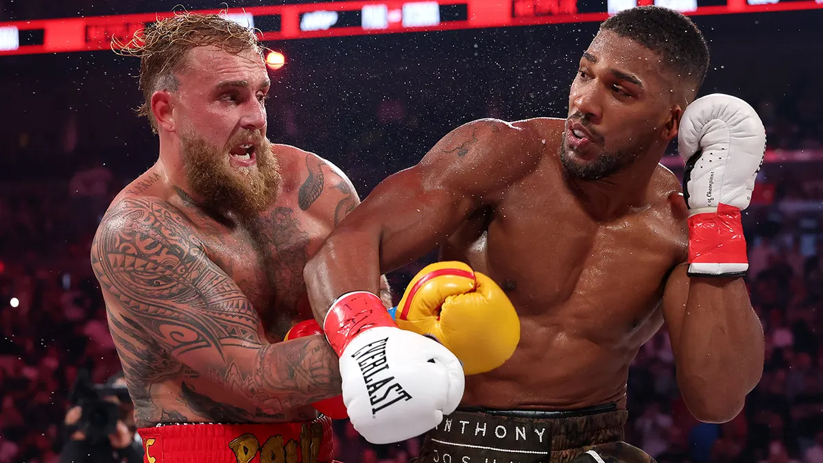 Jake Paul and Anthony Joshua fighting in a boxing ring at Kaseya Center