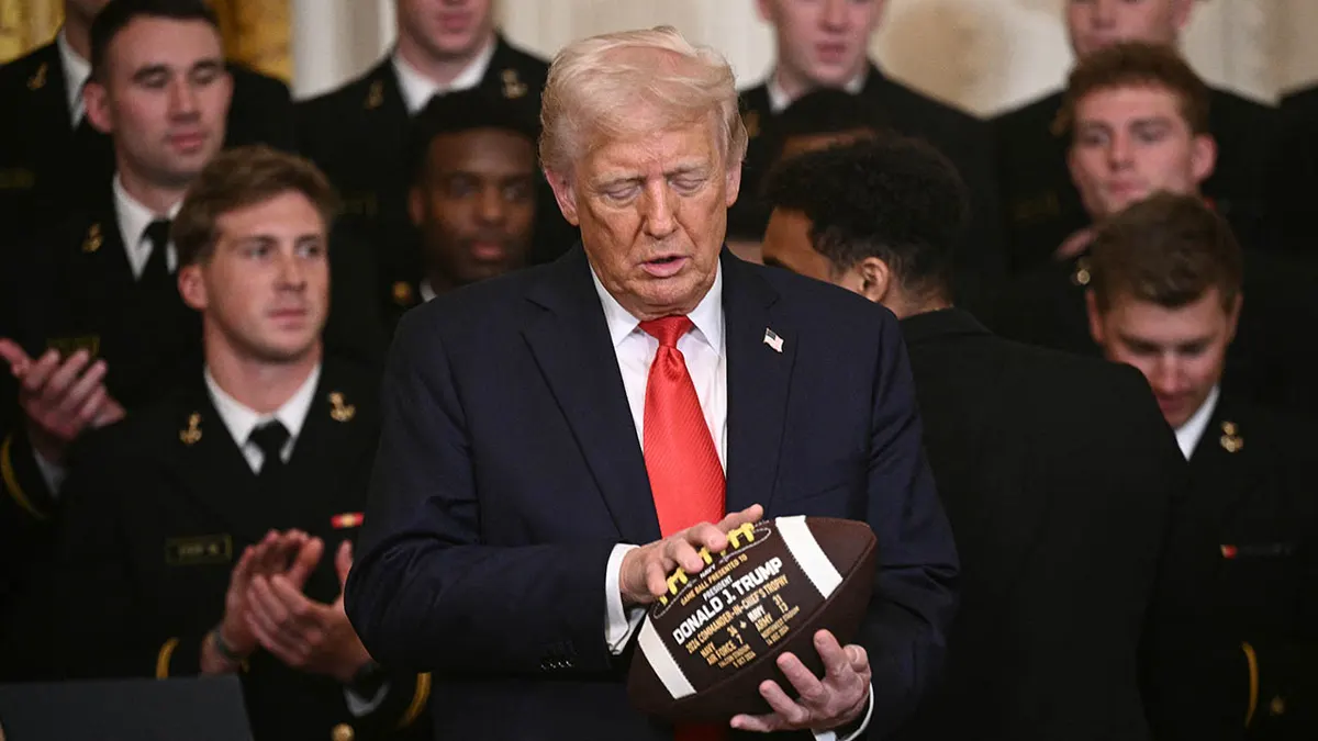 President Donald Trump holding a football in the East Room of the White House.
