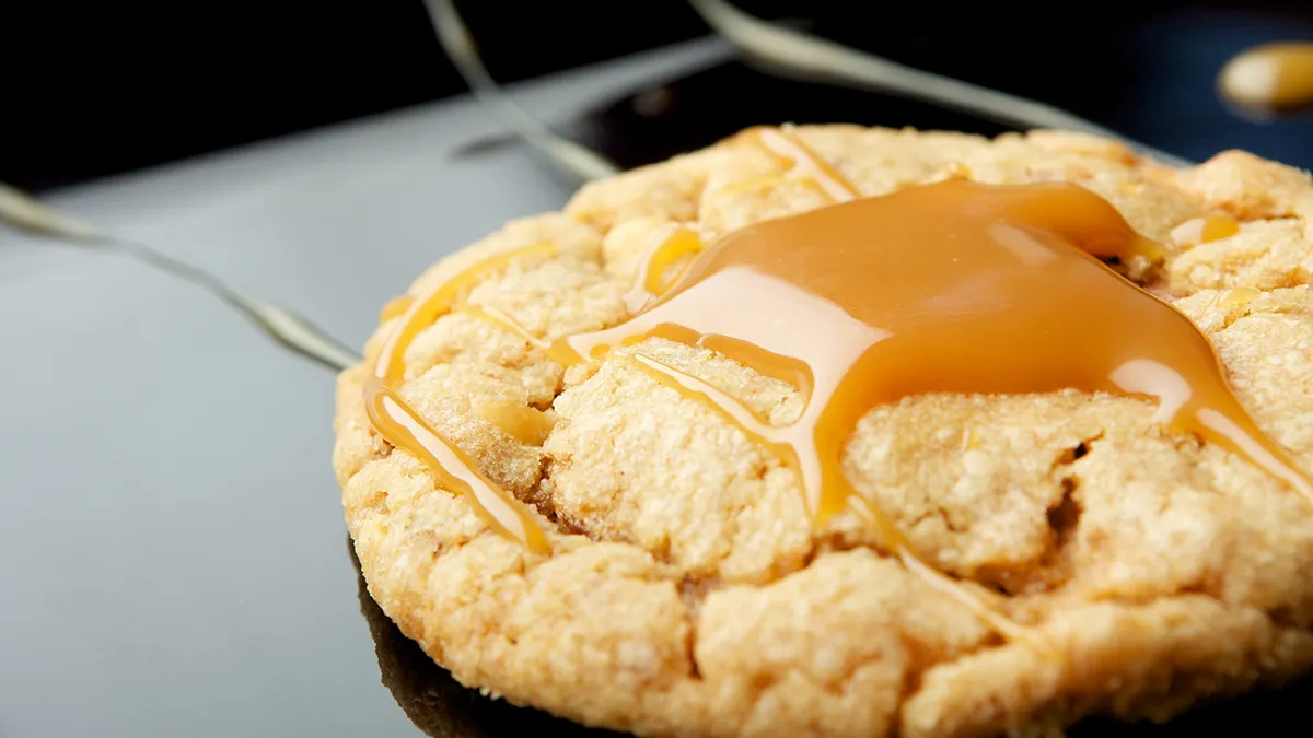 One peanut butter cookie with caramel drizzled on top on a white background