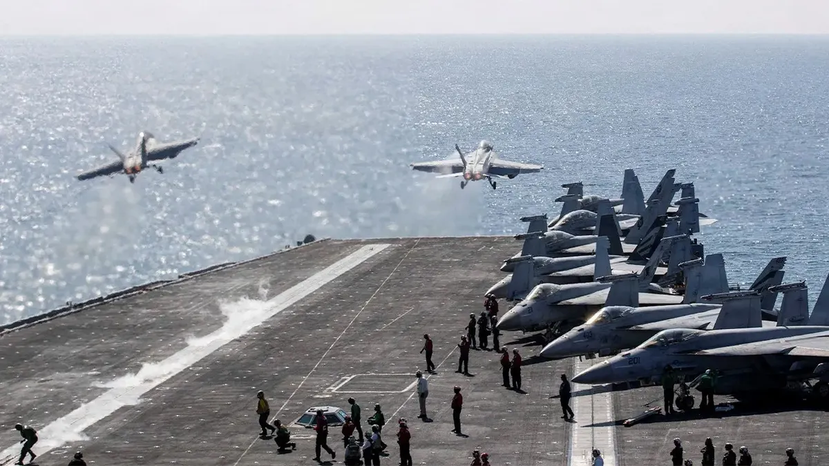 Two F/A-18 Super Hornets launching from USS Abraham Lincoln flight deck.