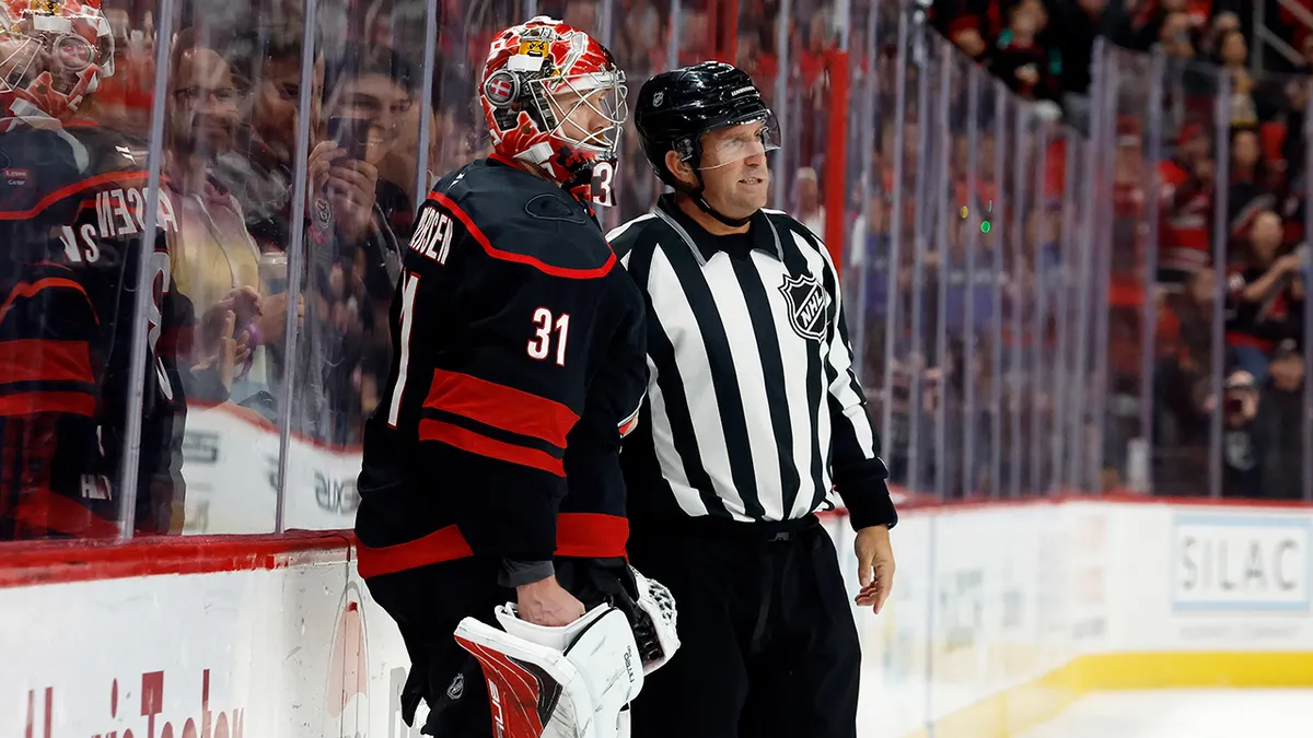 Carolina Hurricanes goaltender Frederik Andersen standing next to an official on ice.