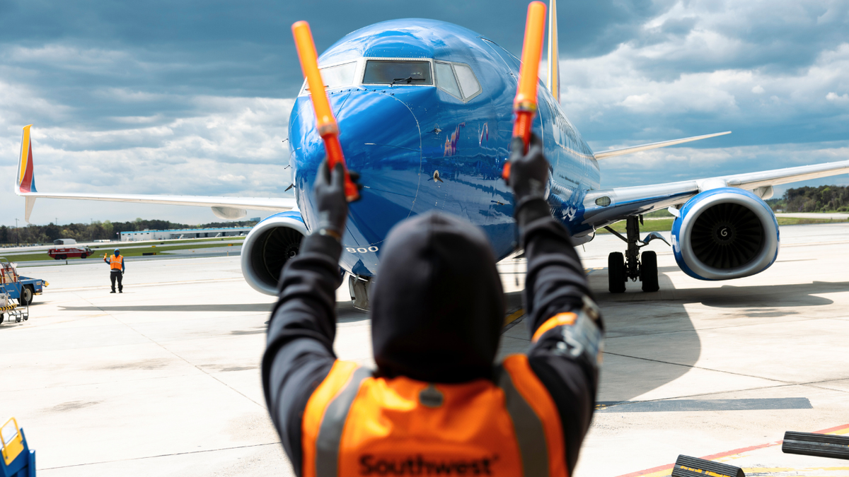 A ramp agent directs a Southwest Airlines Boeing 737-800 airplane at a gate at Baltimore-Washington Airport