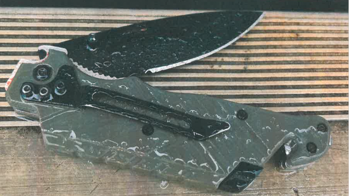 A folding pocketknife with dark blade and gray handle lying on a surface.