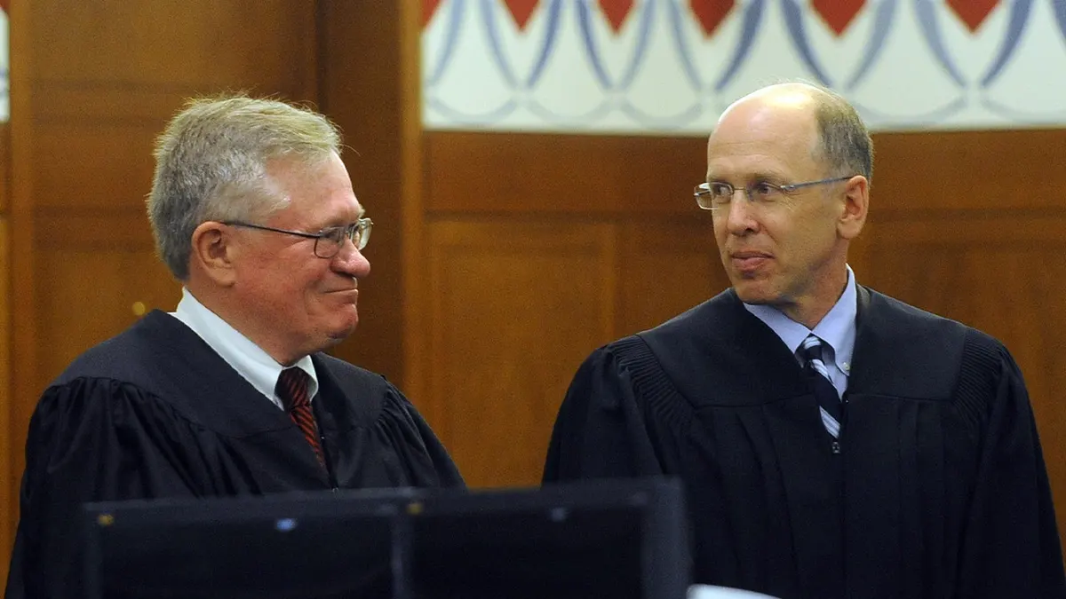 two judges wearing black smile at each other
