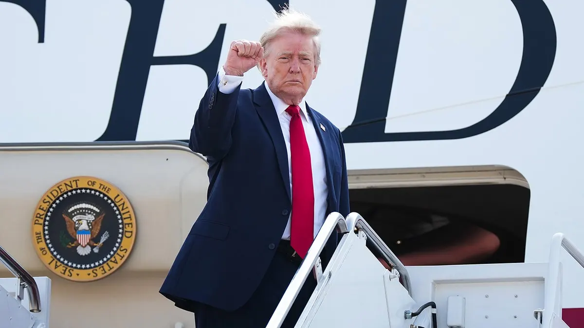 President Donald Trump holds up fist while boarding Air Force One