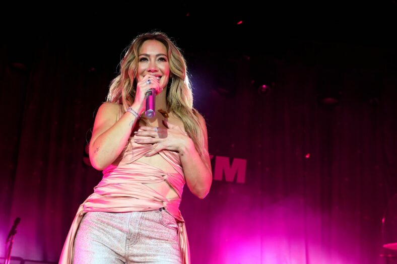 Hilary Duff sorri enquanto se apresenta no palco