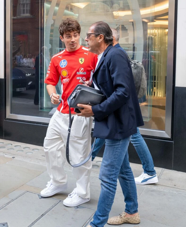 Charles Leclerc conversando com alguém ao sair de uma loja