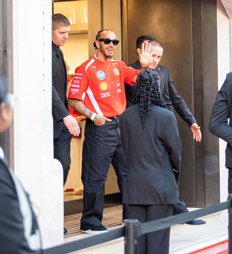 Lewis Hamilton acena para os fãs ao sair da loja da Ferrari