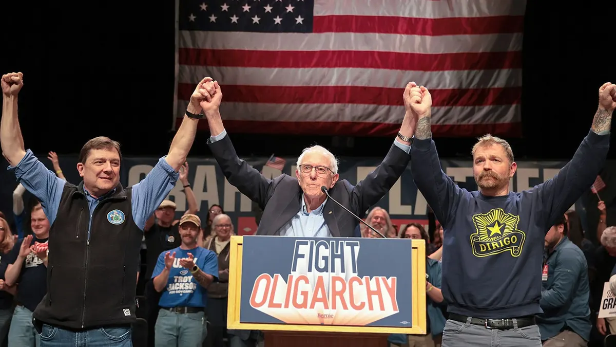 Bernie Sanders standing with Troy Jackson and Graham Platner on a stage.