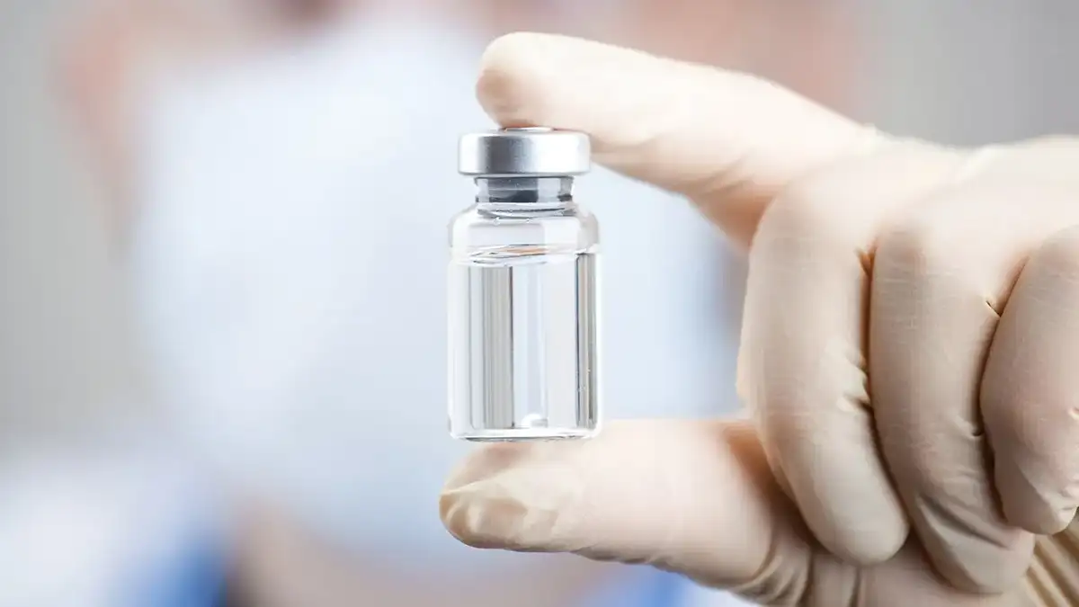 A doctor holding a vial and syringe preparing for injection