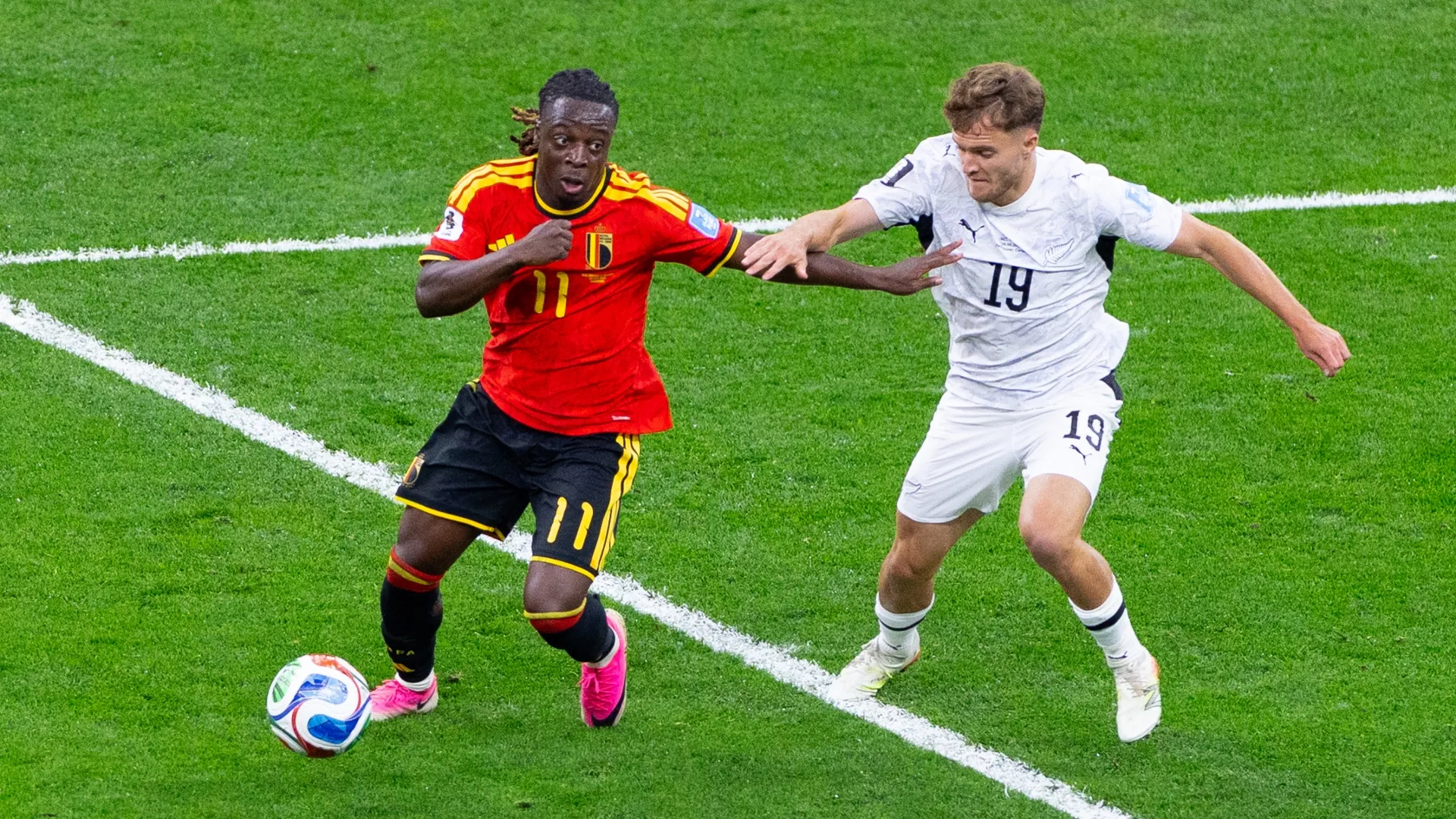 Ben Old, da Nova Zelândia, compete pela bola com Jeremy Doku, da Bélgica.