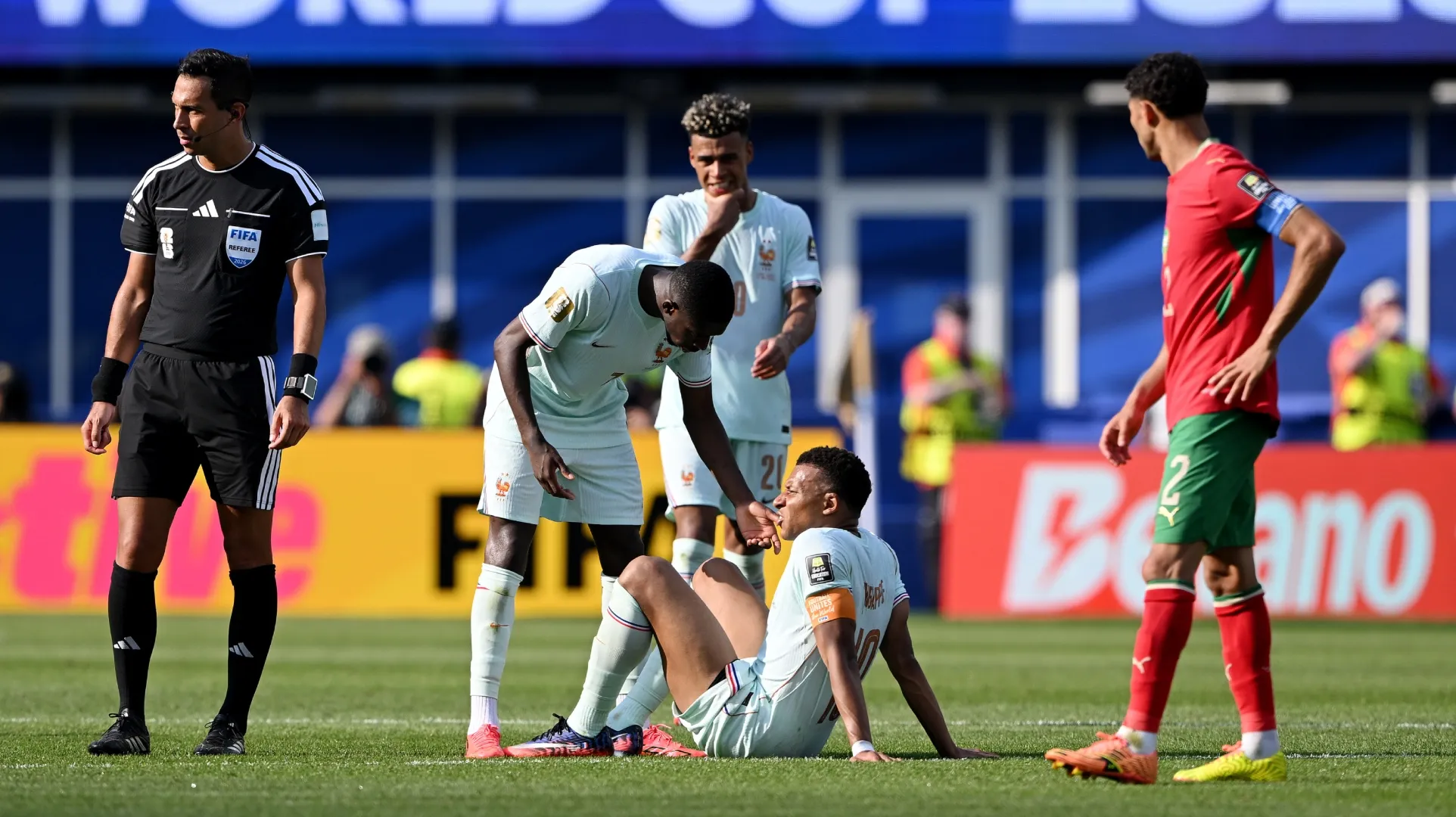 Kylian Mbappe #10 da França é atendido por companheiros de equipe.