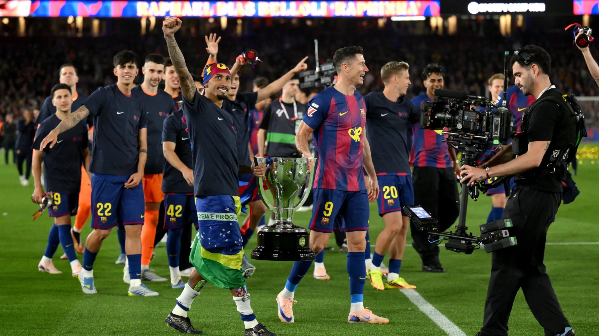 Raphinha e Robert Lewandowski do FC Barcelona carregam o troféu da La Liga 2025-26.