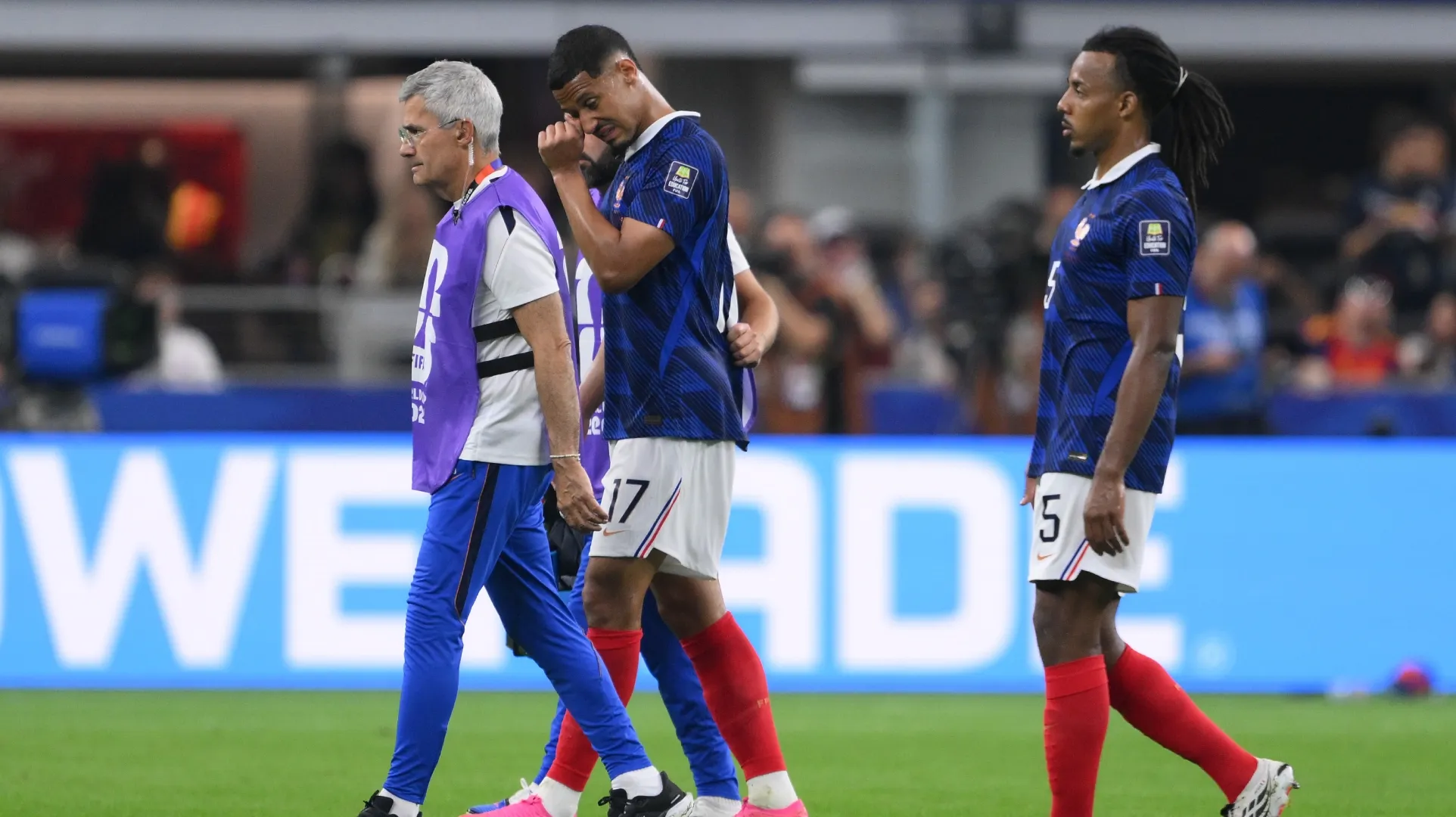 William Saliba, nº 17 da França, sai de campo com a equipe médica após sofrer uma lesão.