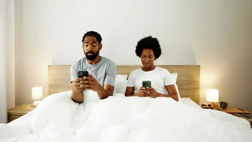 Couple in bed looking at their phones