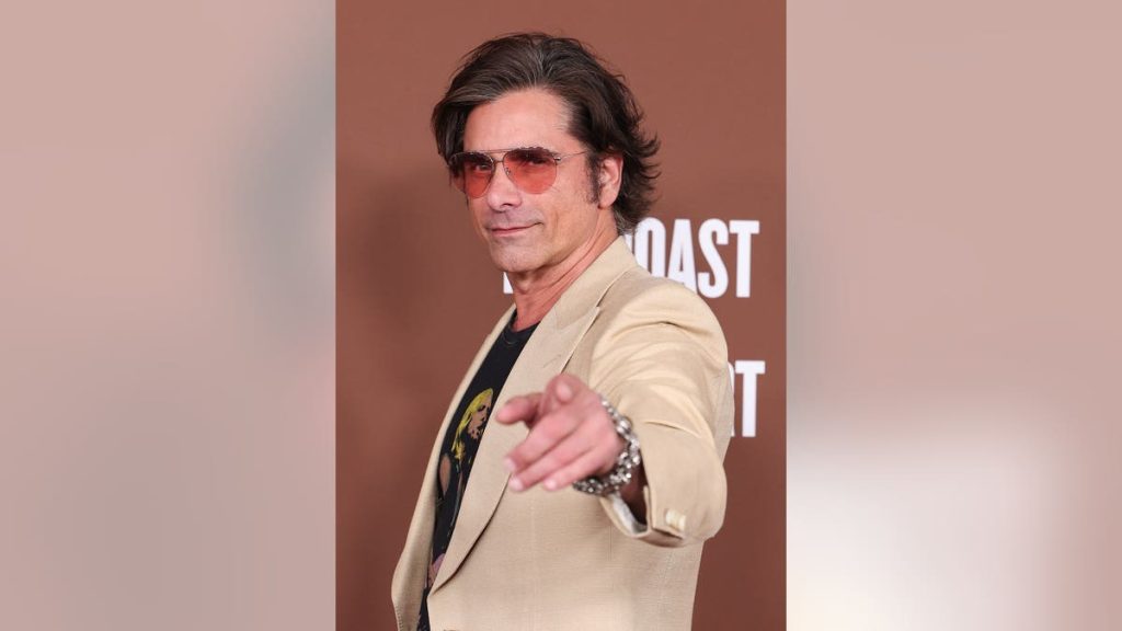 John Stamos standing on the red carpet at The Roast of Kevin Hart event