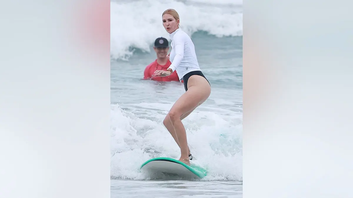 Ivanka Trump surfing in Costa Rica in a white long sleeve and black bottoms in August 2026.