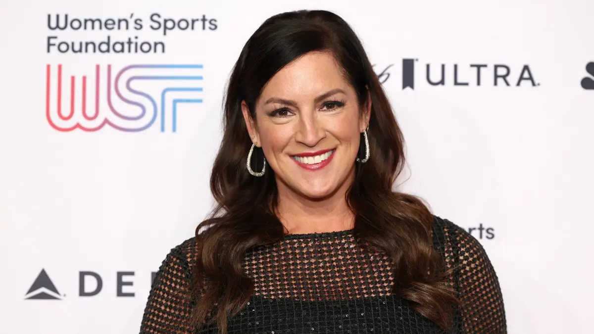 Sarah Spain smiling at a Women’s Sports Foundation event in front of a WSF backdrop.