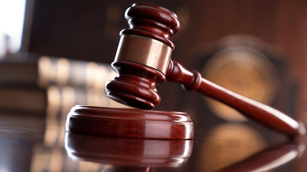 A gavel, legal books, and a statue of Themis on a judge
