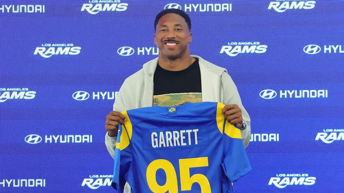 Myles Garrett of the Los Angeles Rams posing with his jersey at a press conference.