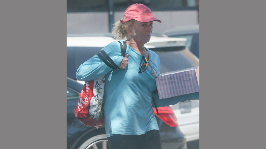 Linda Purl carrying a cake outside of a Gelson