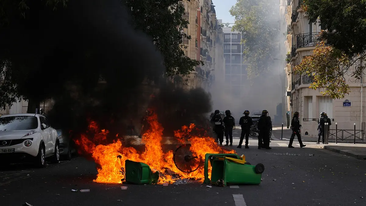 Policemen stand in front of burning garbage during a student protest in Paris.