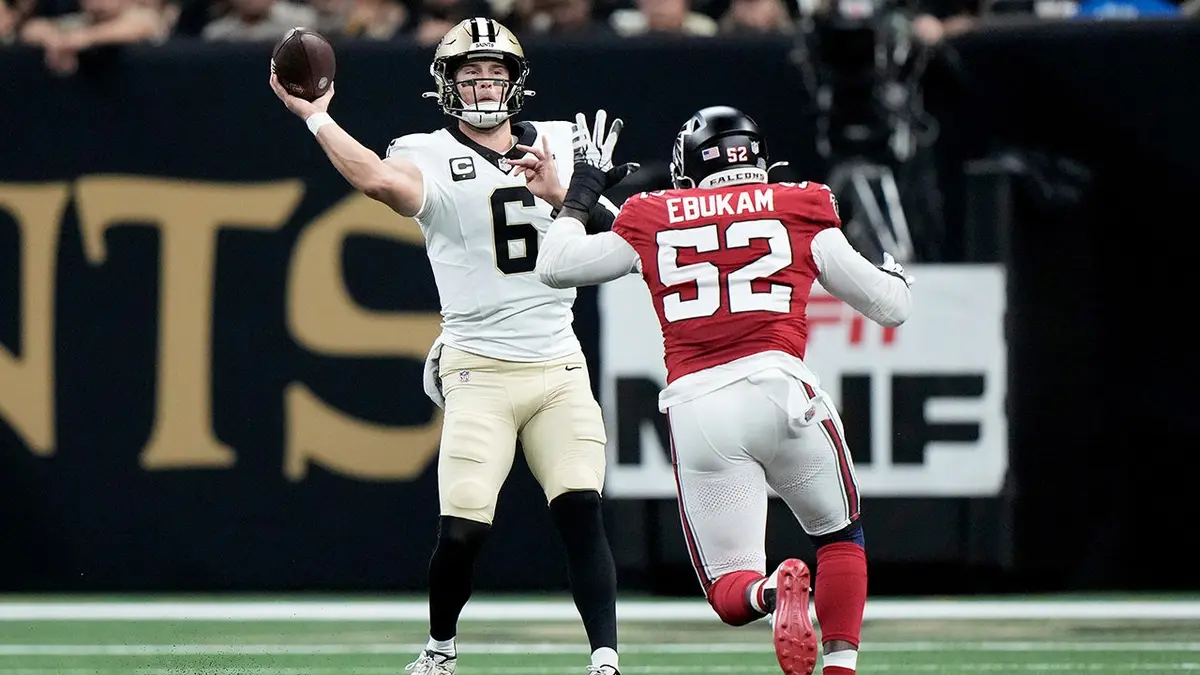 Tyler Shough passes as Samson Ebukam applies pressure during an NFL game.