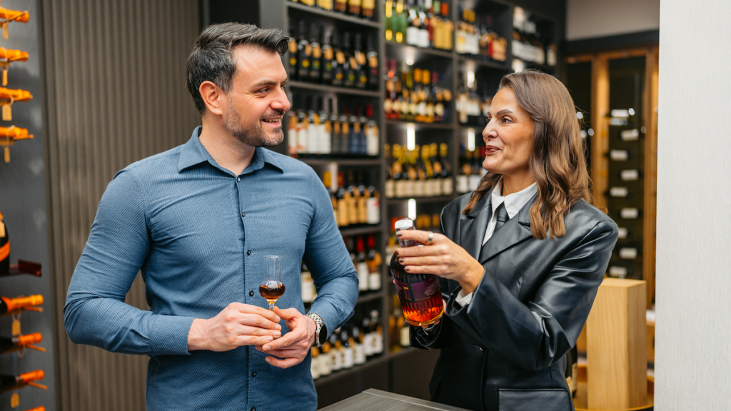Saleswoman helps a man choose whiskey while tasting in a liquor store.