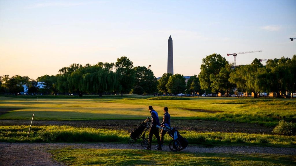 People playing golf at East Potomac Golf Links with Washington Monument in background